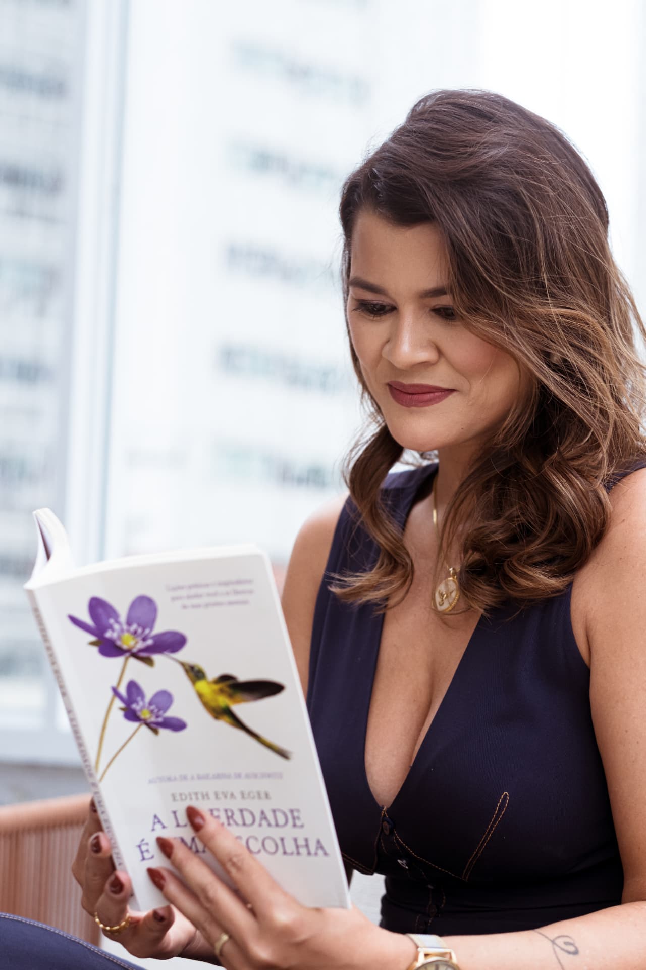 Juliana lendo um livro em um ambiente claro