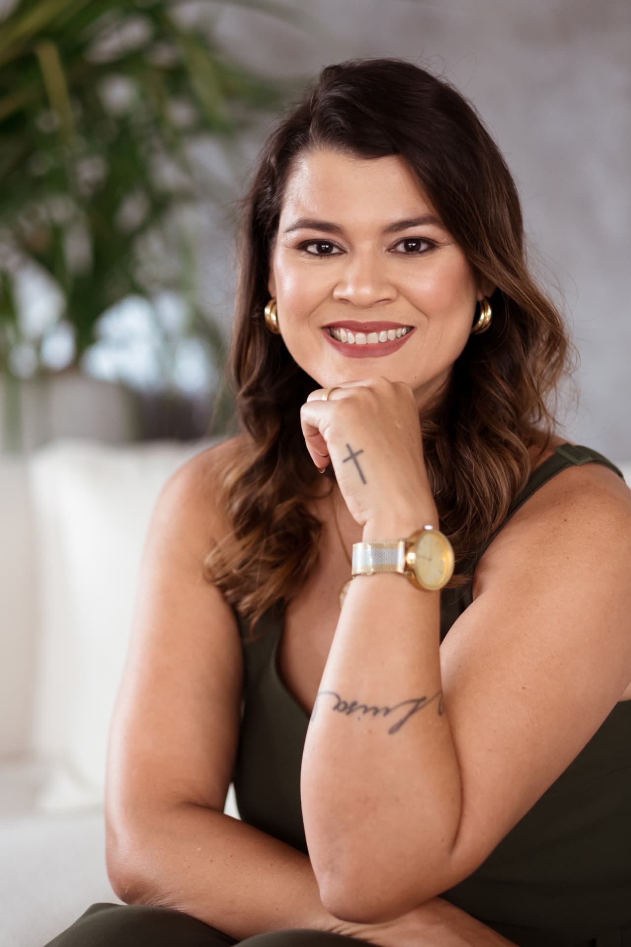 Retrato de Juliana sorrindo, sentada com uma planta ao fundo